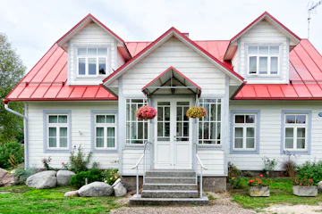 Maison blanche au toit rouge avec lucarnes et perron