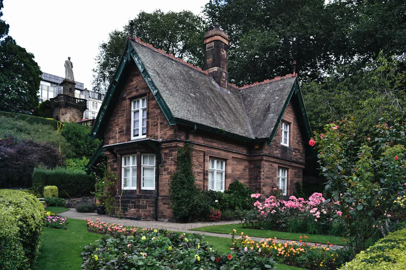 Maison en pierre au toit d'ardoise entourée d'un jardin fleuri