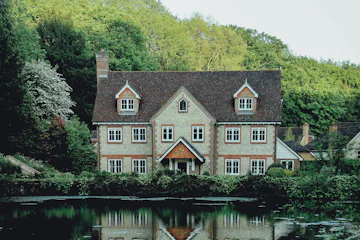 Manoir à colombages au bord d'un étang entouré de forêt