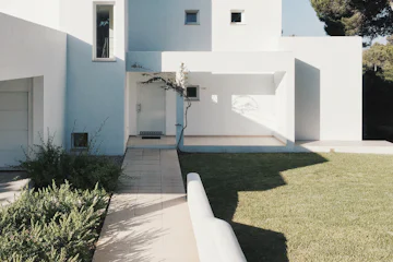 Maison d'architecte aux volumes blancs et pelouse