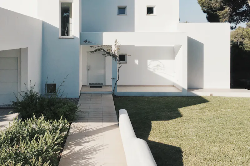 Maison d'architecte aux volumes blancs et pelouse